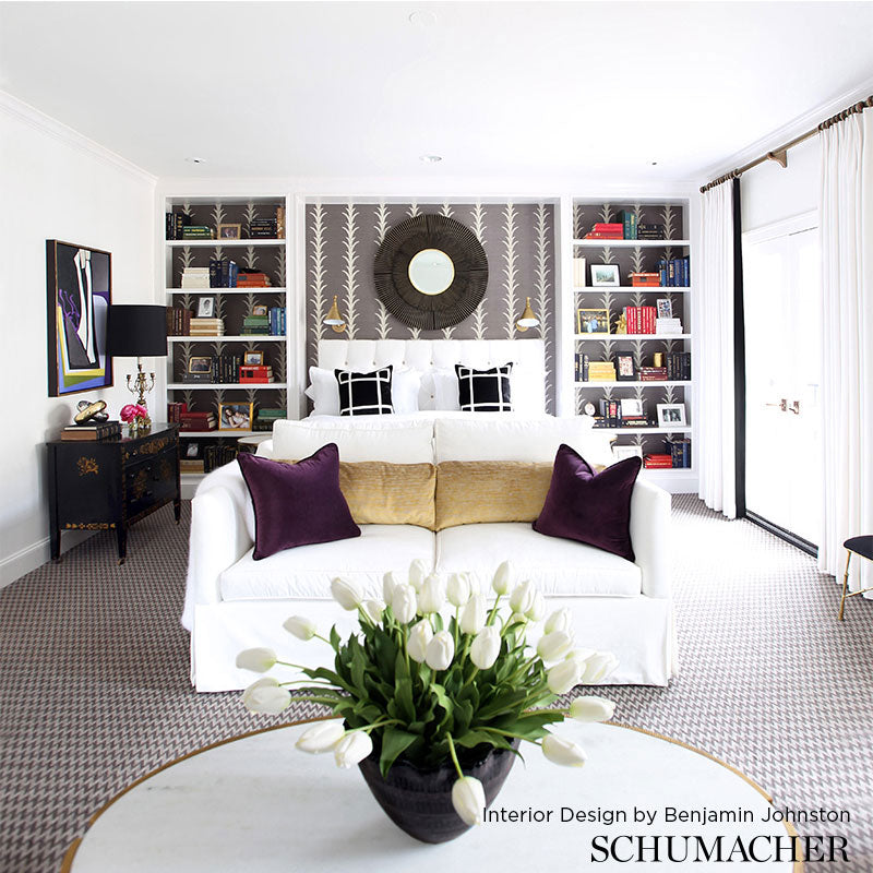 Modern white living room with white sofa, purple & gold cushions, round mirror, built-in bookcases, featuring acanthus stripe sisal filigree wallcovering.