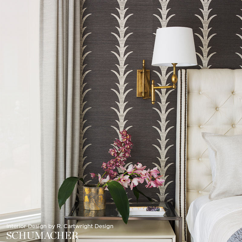 Luxurious bedroom with charcoal acanthus stripe sisal filigree wallpaper, gold sconce, tufted headboard, glass bedside table, pink orchids.