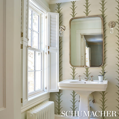 Bathroom scene with olive acanthus stripe wallpaper, white pedestal sink with chrome faucets, oval-framed mirror, and a window with shutters.