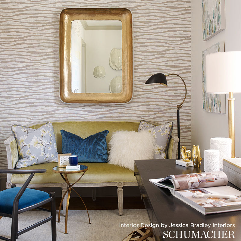 Mustard sofa with blue/white pillows and fluffy white throw, gold mirror, zebra wallpaper, arc lamp, glass coffee table.