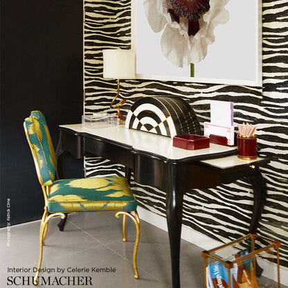 Vanity desk with zebra wallpaper, black curved legs, teal-gold chair, lamp, and bold black‑and‑white art.