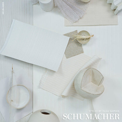 Ivory textured chevron wallcovering swatch flat lay with fabric swatches, textured papers, a ceramic heart bowl and dried plant accents.