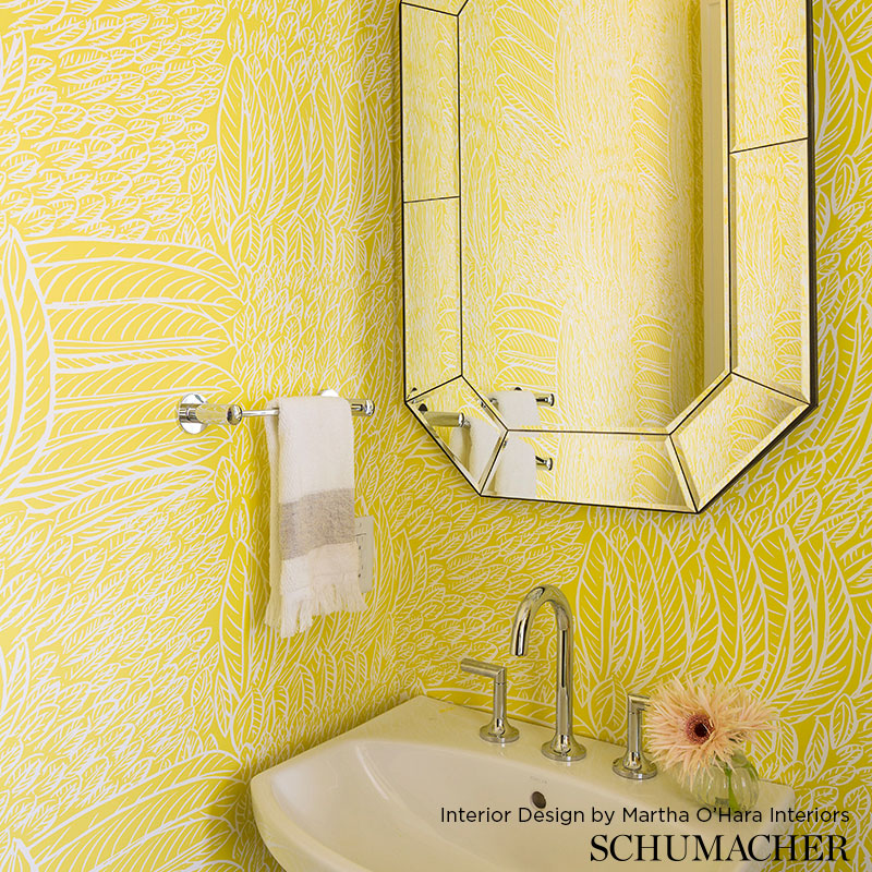 Bright yellow patterned bathroom with hexagonal mirror, white sink, chrome faucet, towel bar, and a flower on the counter.