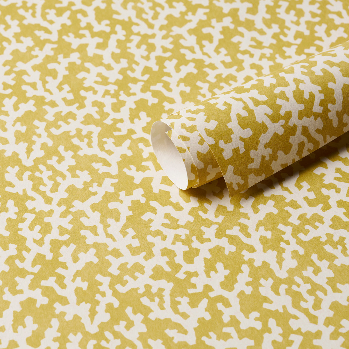 Mustard-yellow wrapping paper with white abstract cross-like pattern; rolled sheet.