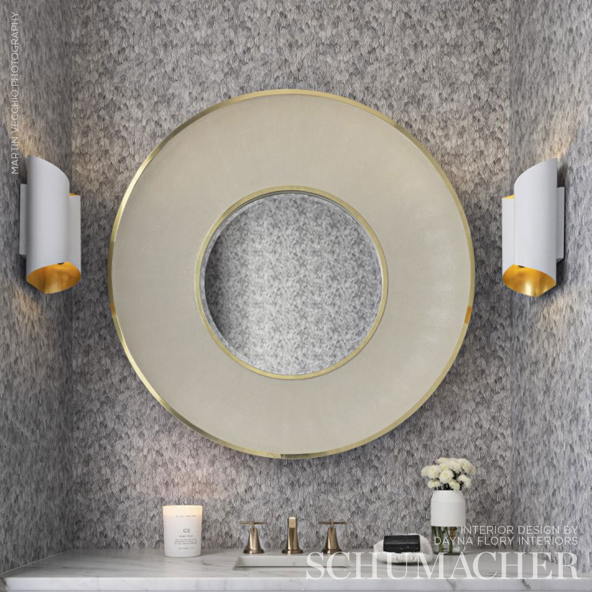 Donut-shaped frosted glass wall light with gold rim on gray textured wall, beside white and gold sconces.