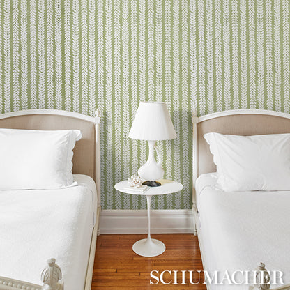 Two twin beds with white bedding & beige headboards, white nightstand with lamp, green leafy wallpaper & wood floor.