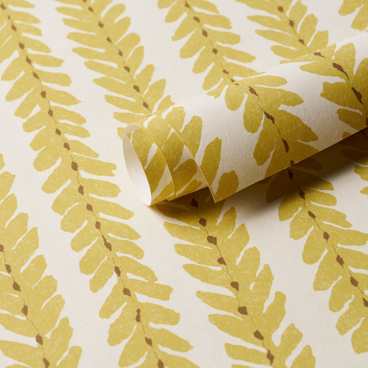 Yellow fern-pattern wallpaper on white backdrop; rolled corner shows paper texture, botanical wallcovering.