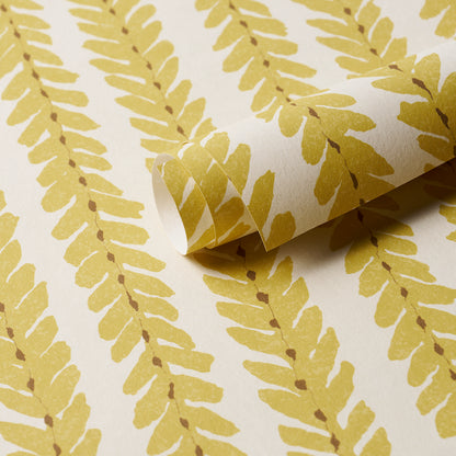 Yellow fern-pattern wallpaper on white backdrop; rolled corner shows paper texture, botanical wallcovering.