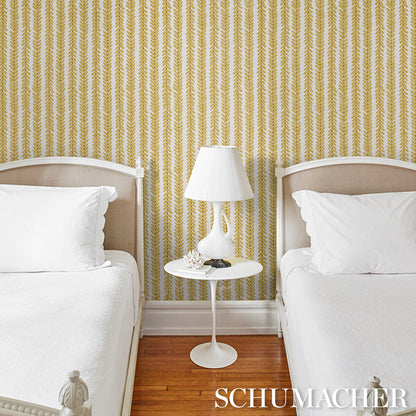 Twin bedroom with white bedding, beige headboards, gold leaf-pattern wallpaper, white round nightstand and lamp, maple floor.