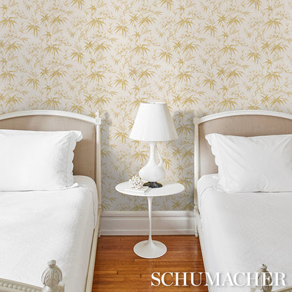 Twin beds with white linens, round white pedestal nightstand, ceramic lamp; palm-leaf wallpaper and wood floor.