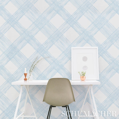 White desk with olive mid-century chair; blue plaid wallpaper, leaning print with two gray circles, and potted plants.