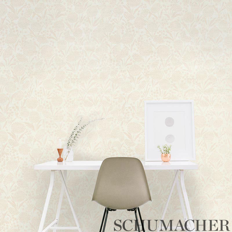 Beige damask wallpaper, white desk with taupe molded chair, framed art, vase of dried grass, and orange-potted plant.