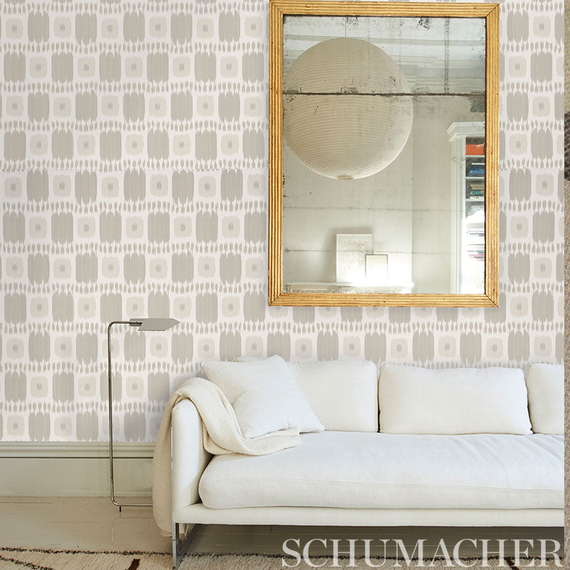 Geometric wallpaper in wheat tones behind a neutral sofa with a throw and cushions.