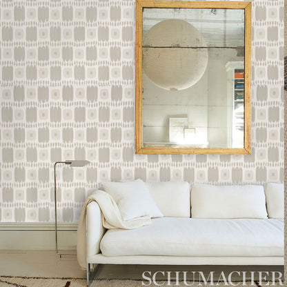 Geometric wallpaper in wheat tones behind a neutral sofa with a throw and cushions.
