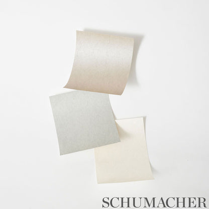 Three textured pastel wallcovering swatches in beige, gray, and cream with curled corners, arranged in a curved vertical line.