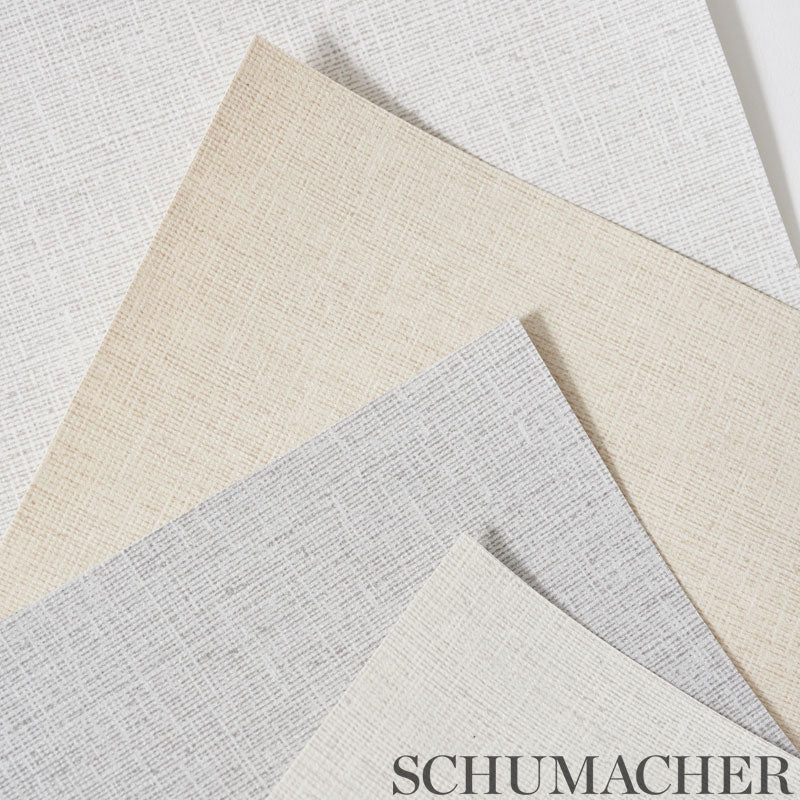Schumacher wallcoverings swatches in beige, taupe, and gray with a linen-like woven texture, overlapping.