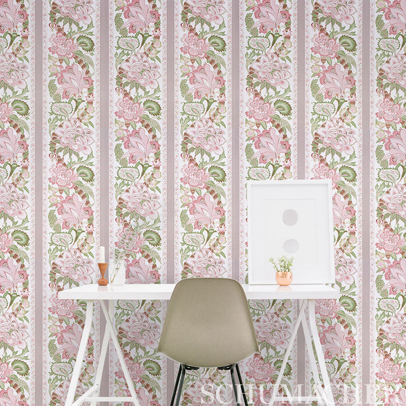 Beige molded chair at white desk set against pink floral striped wallpaper; leaning frame, small plant and vase on desk.
