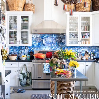 Bright farmhouse kitchen with blue-and-white tile backsplash, stainless range, and a metal-topped island with wicker base.