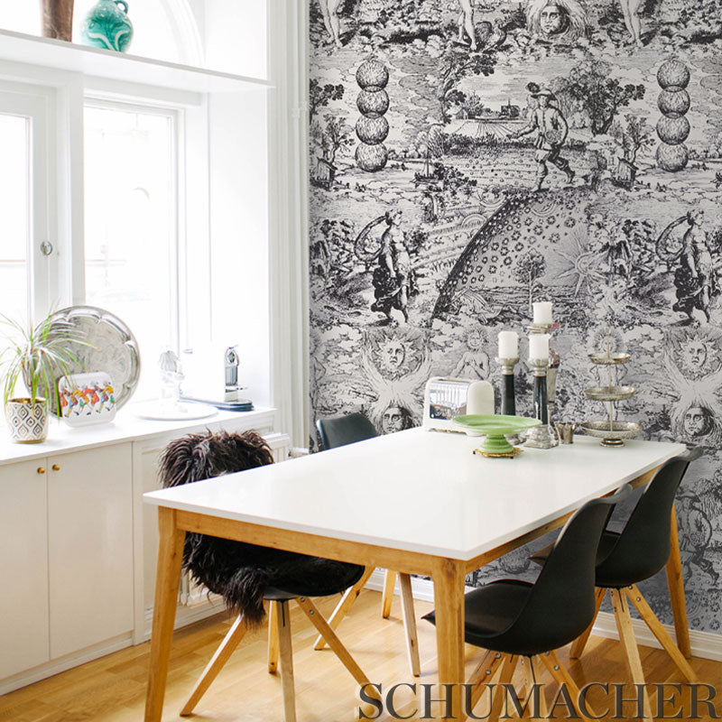 White rectangular dining table with wooden legs & black mid-century chairs, against bold black-&-white damask wallpaper backdrop.