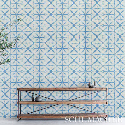 Rustic wood-and-metal console shelves set against blue geometric tile wallpaper, with ceramic decor pieces and a leafy branch on the left.