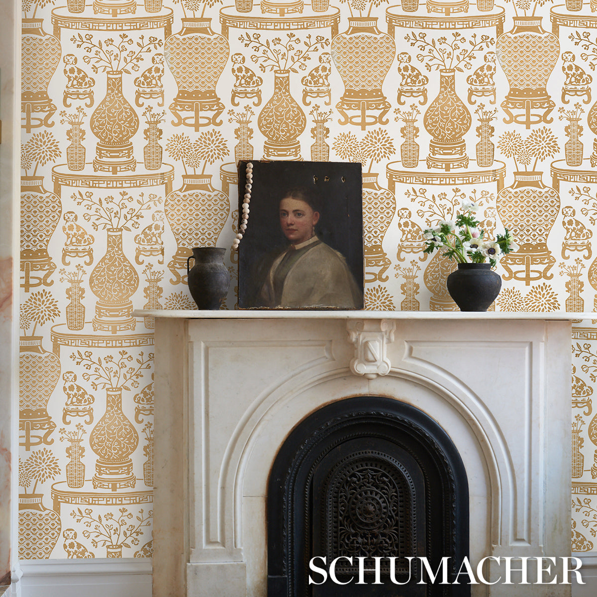 Marble fireplace with ornate black cast-iron insert, gold-pattern wallpaper, portrait on mantel, dark vase & white flowers.