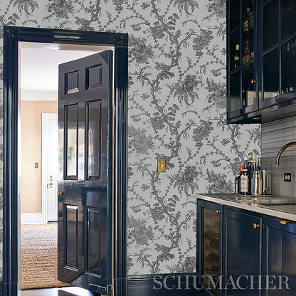 Dark navy paneled door opens to beige foyer; grey botanical wallpaper, navy cabinets, marble countertop and wine cooler.