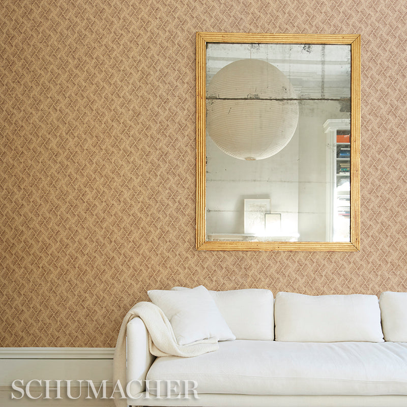 Cream sofa with white cushions and throw, grey woven wallpaper, gold-framed rectangular mirror above.