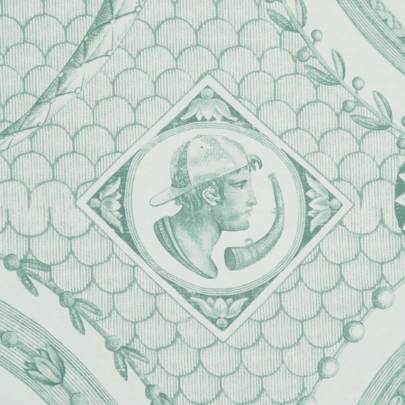 Mint-green patterned wallpaper with a fish-scale motif and a diamond frame containing a horned-creature emblem; botanical borders.