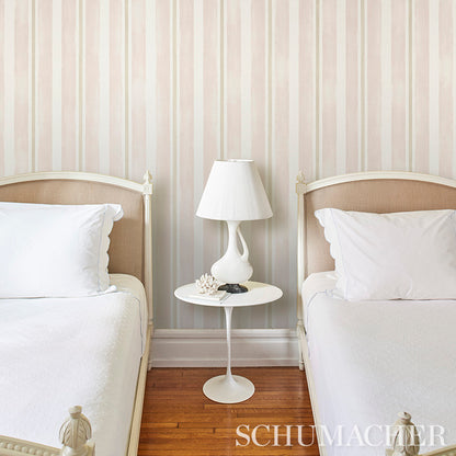 Twin beds with white bedding and beige headboards, white round nightstand and lamp between them, pastel lavender striped wallpaper.