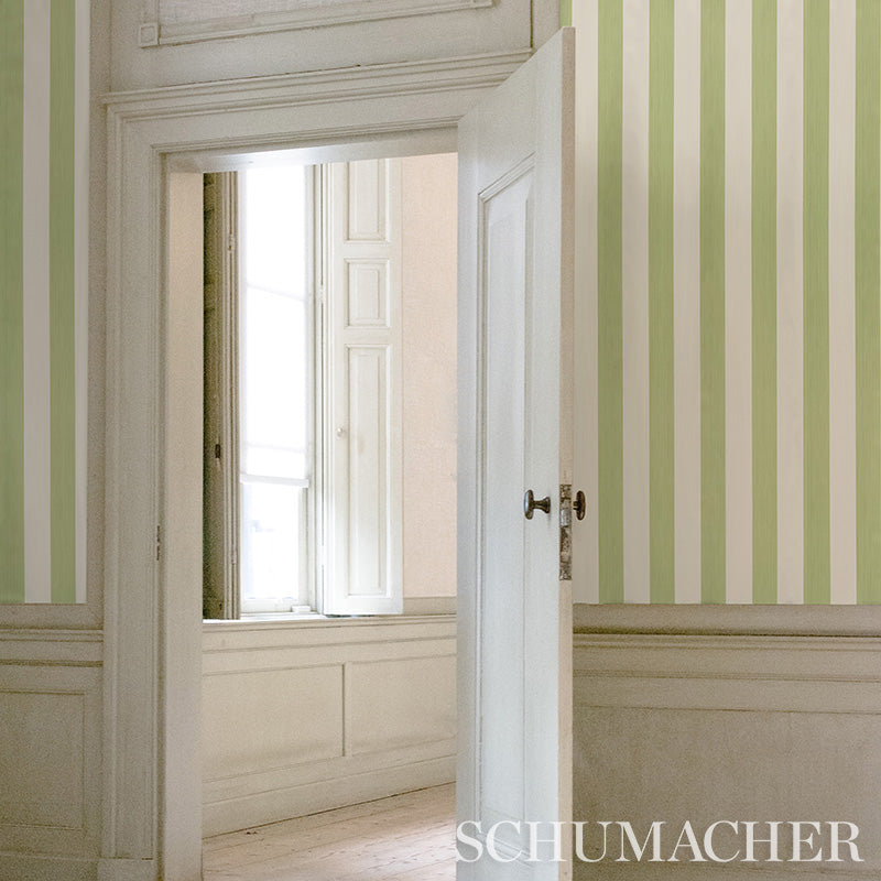 Open white door reveals pale green and cream vertical striped wallpaper with white wainscoted panels.
