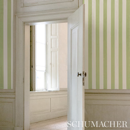 Open white door reveals pale green and cream vertical striped wallpaper with white wainscoted panels.