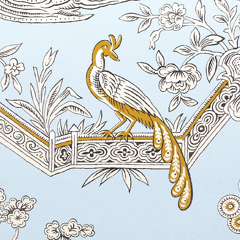Gold and white peacock perched on an ornate balcony railing against pale blue floral wallpaper.