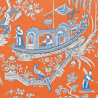 Orange textile with a blue-and-white ornate boat scene, people aboard, a peacock and floral details.