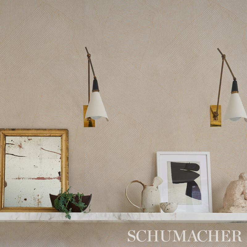 Beige textured wall with two white-cone wall sconces, marble shelf, plant, ceramic pitcher, and gold-framed artwork.