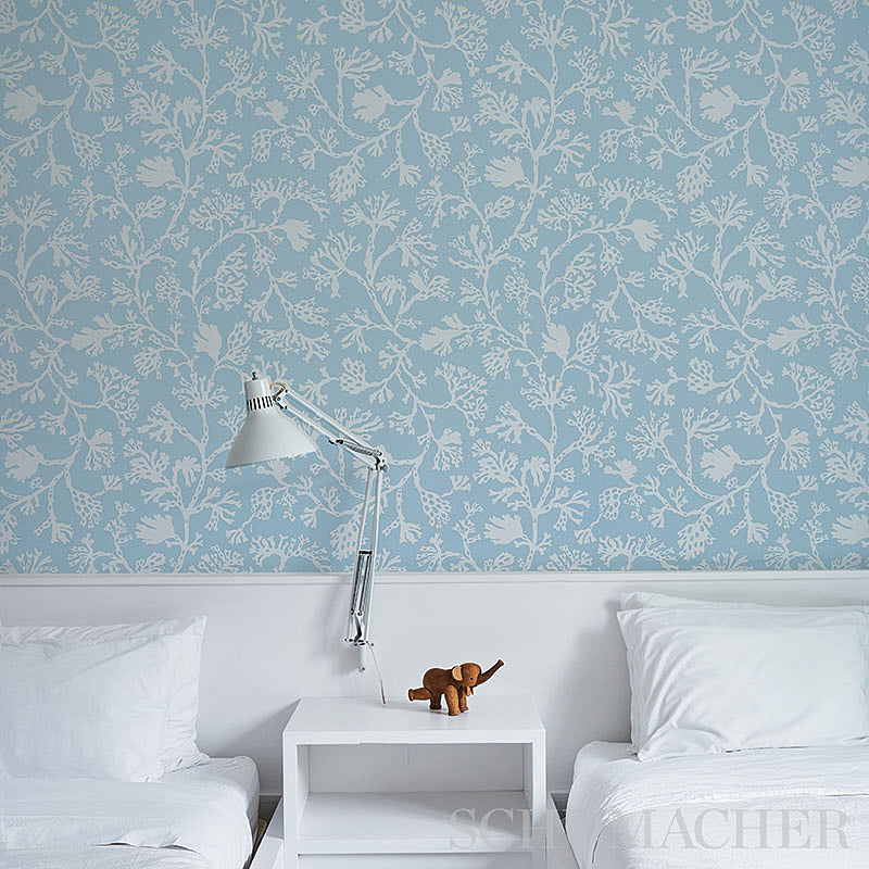 Blue wallpaper with white botanical pattern; bedroom scene with white beds, silver adjustable lamp, white nightstand, and wooden elephant decor.