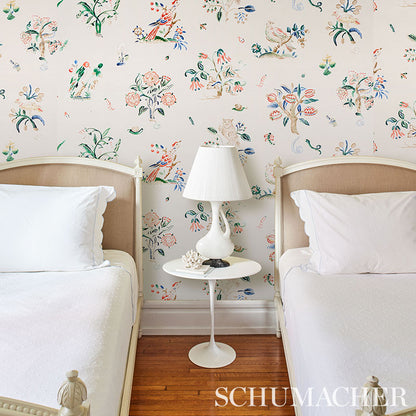 Twin beds with white bedding and beige headboards, white round nightstand and lamp, colorful floral wallpaper backdrop.