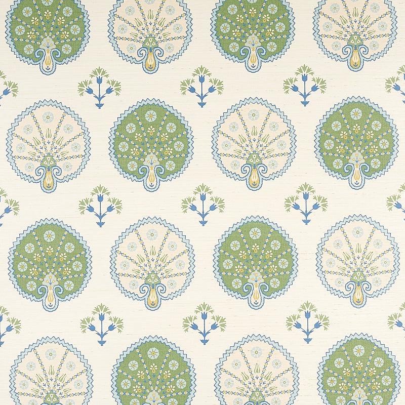 Wallpaper pattern of green and beige tree medallions with blue scalloped borders, interspersed by small blue flowers on cream.