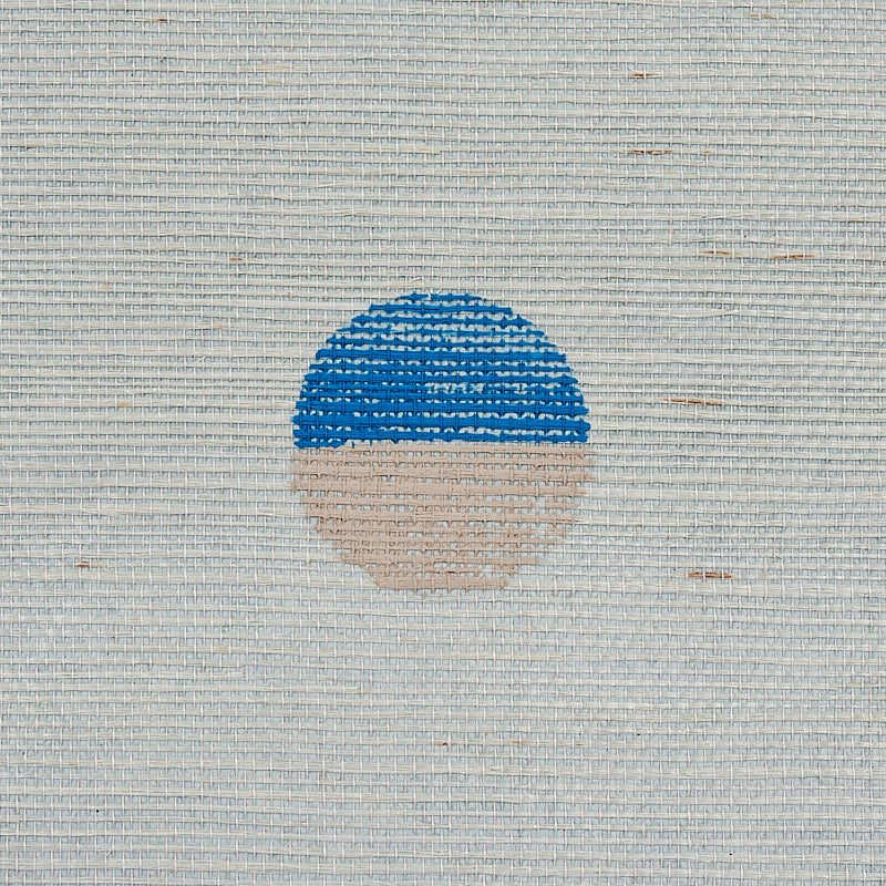 Circular sun icon with blue striped upper half and peach lower half on woven beige sisal rug.