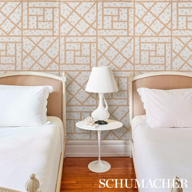 Twin beds with beige upholstered headboards, white bedding, round white nightstand and lamp between; beige geometric wallpaper; wood floor.