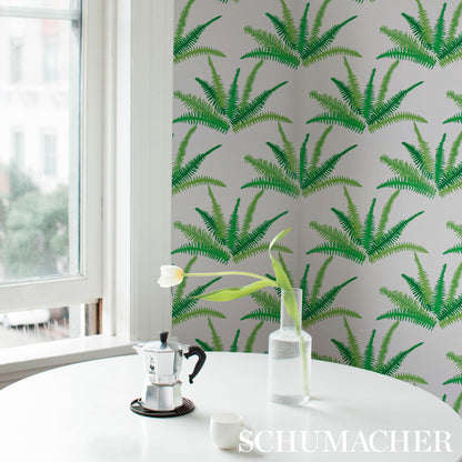 Bright dining nook with fern-pattern wallpaper, round white table, moka pot on a coaster, glass vase with a white tulip.