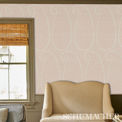 Beige grasscloth wallpaper with a soft blush paisley sisal pattern on a wall.