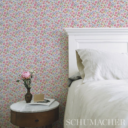 White wooden bed with a marble-topped round nightstand, pastel floral wallpaper, pink peony vase, book and card.