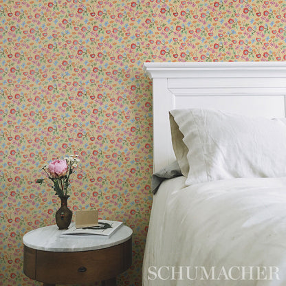 Pastel floral wallpaper with pink, yellow and blue blossoms; a white paneled bed and a round wooden nightstand with a pink vase visible in the room.
