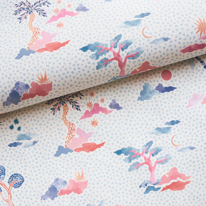 Pastel watercolor fabric with island-tree motifs, clouds and moons in pink, coral and blue on a pale blue background.