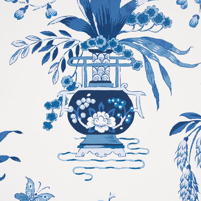 Blue and white porcelain Ming vase with a floral bouquet, ornate handles, surrounded by botanical leaves in a wallpaper pattern.