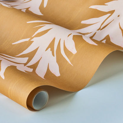 Rolled wallpaper featuring a white lotus design on a deep yellow backdrop, curved edge resting on a pale surface.