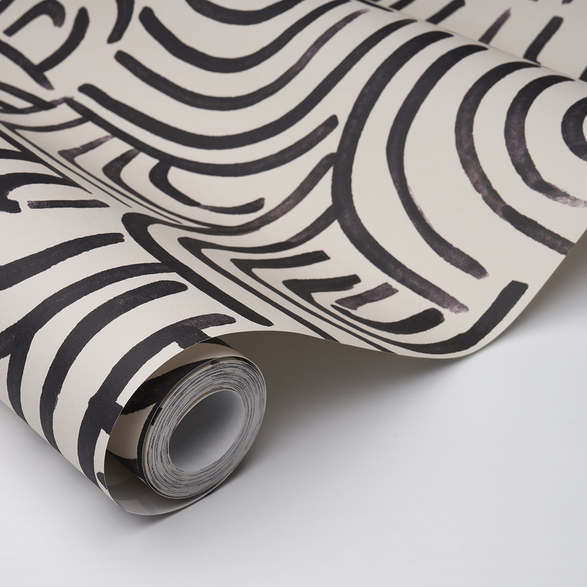 Roll of carbon-colored wallpaper with bold abstract black wavy stripes, partially unrolled.