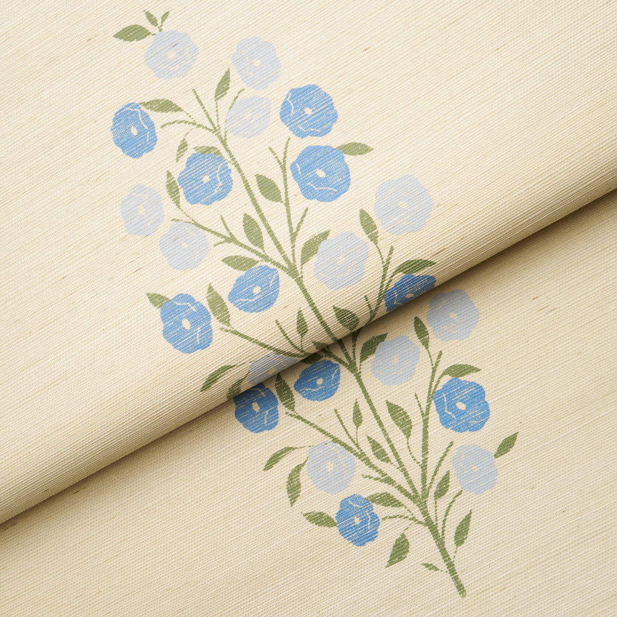 Beige sisal wallpaper with blue floral print, green stems and leaves; rolled fold showing delicate blossom pattern.
