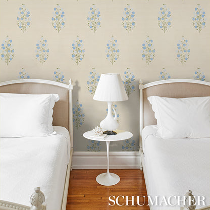 Twin bedroom with white bedding, beige upholstered headboards, white round nightstand and lamp, blue floral wallpaper.