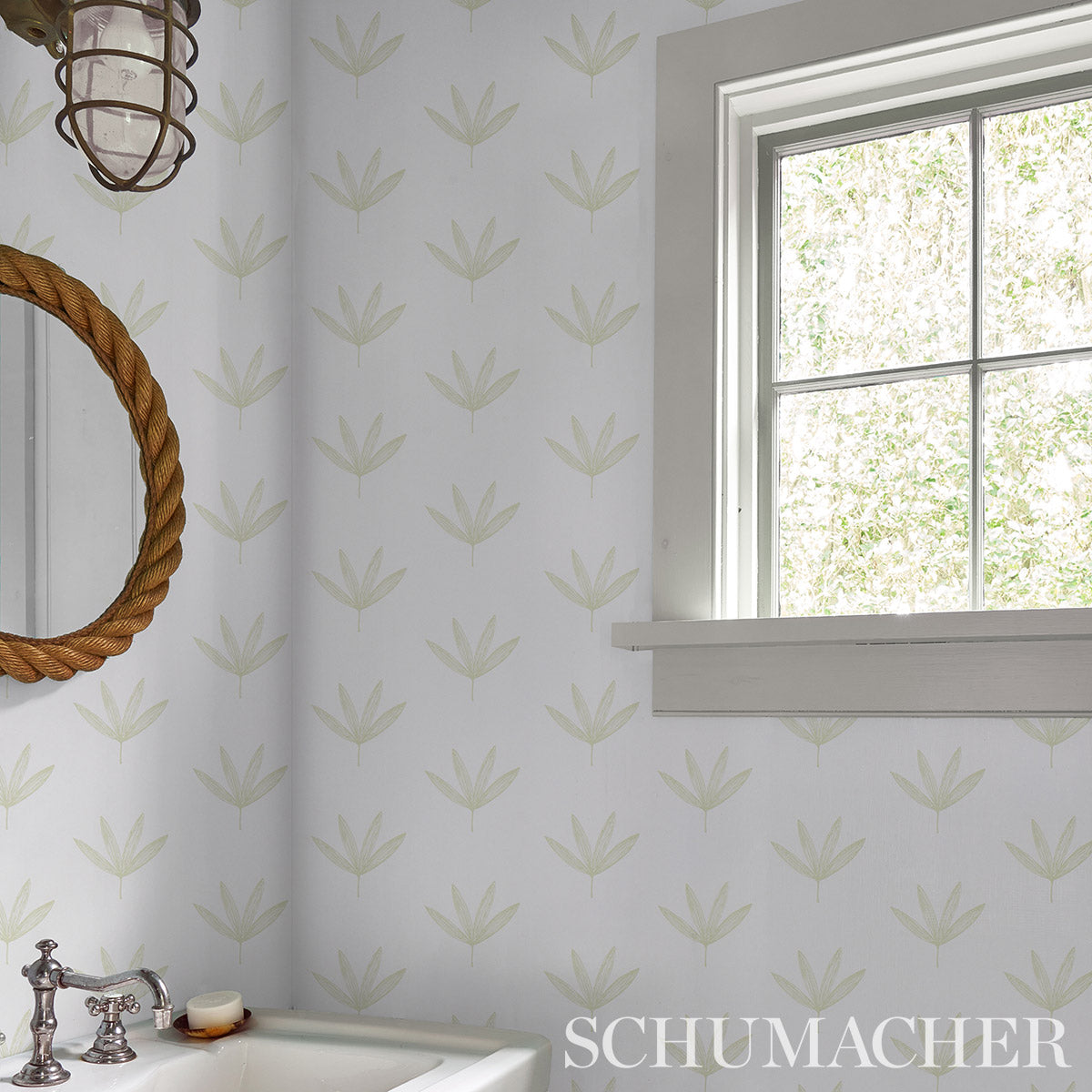 Bathroom with pale green leaf-pattern wallpaper, rope-framed round mirror, vintage chrome faucet over tub, bright window